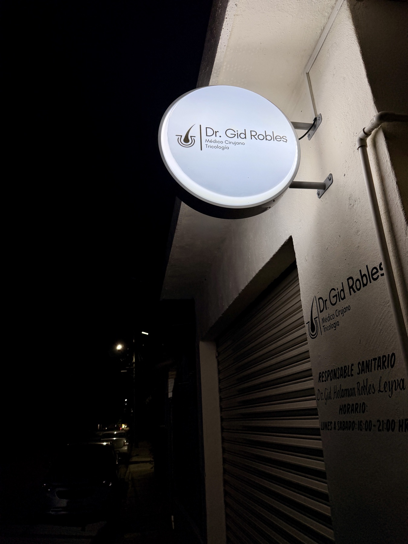 Letrero iluminado del consultorio Dr. Gid Robles en la fachada, de noche